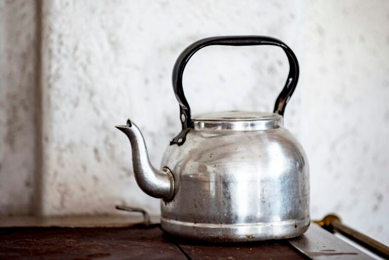 A stainless steel kettle on a wooden kitchen table